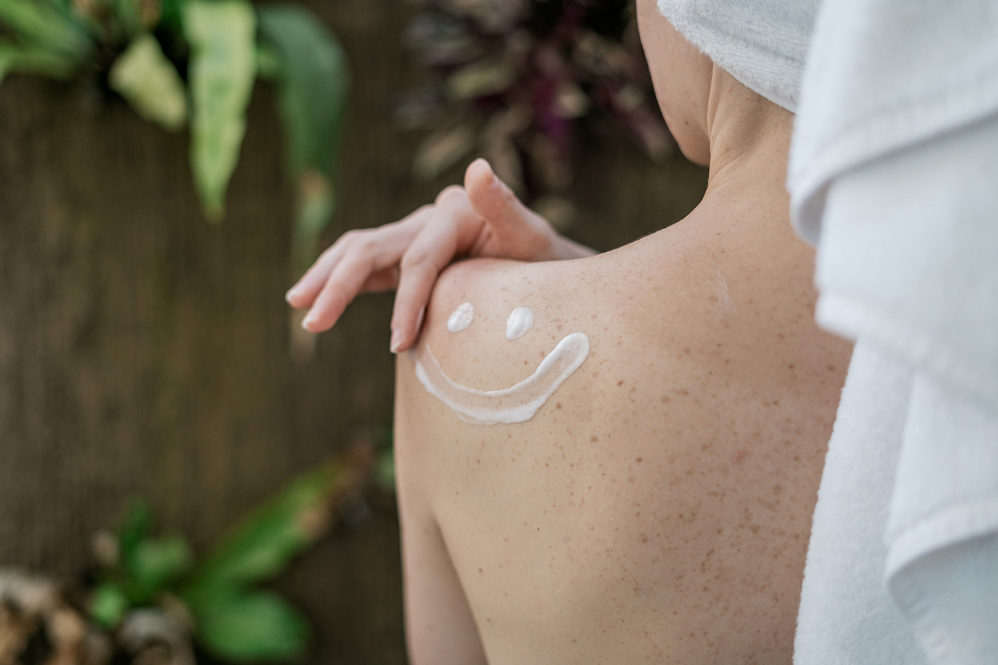 Back of a woman with a smiley out of lotion on her shoulder